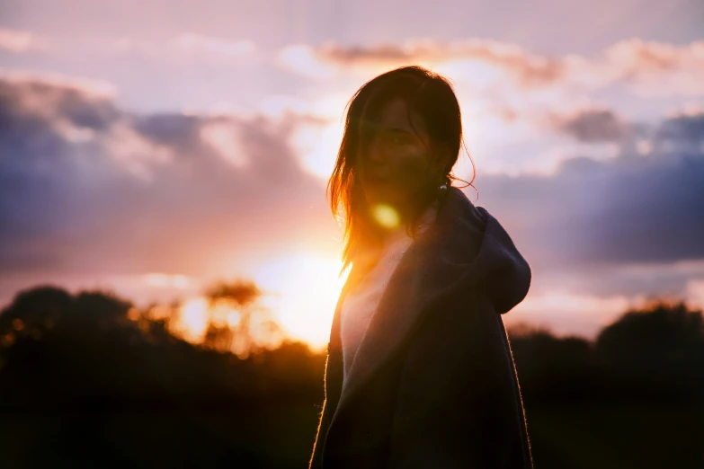 a person in a field with the sun in the background