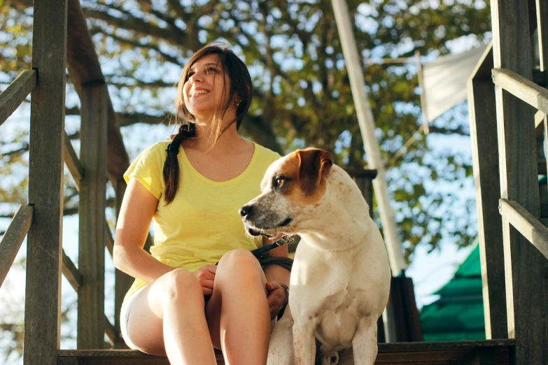 the woman is sitting with her dog on the stairs