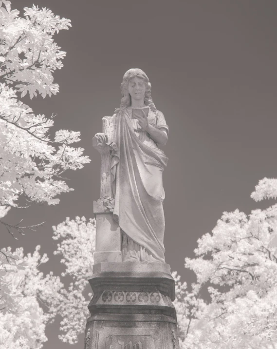 a statue with a very large head next to some trees