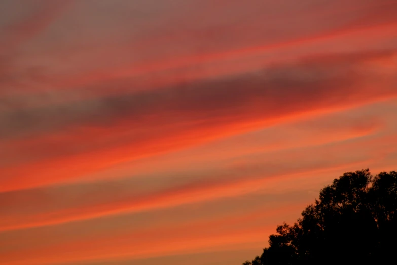 orange clouds with an orange sky and a plane in the background