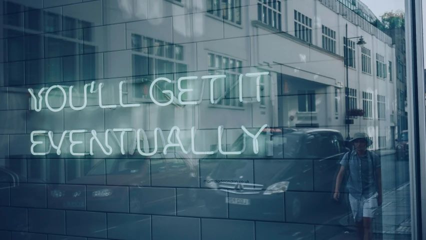 a person walking by a window with neon writing