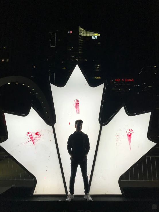 the man is standing in front of an illuminated maple leaf