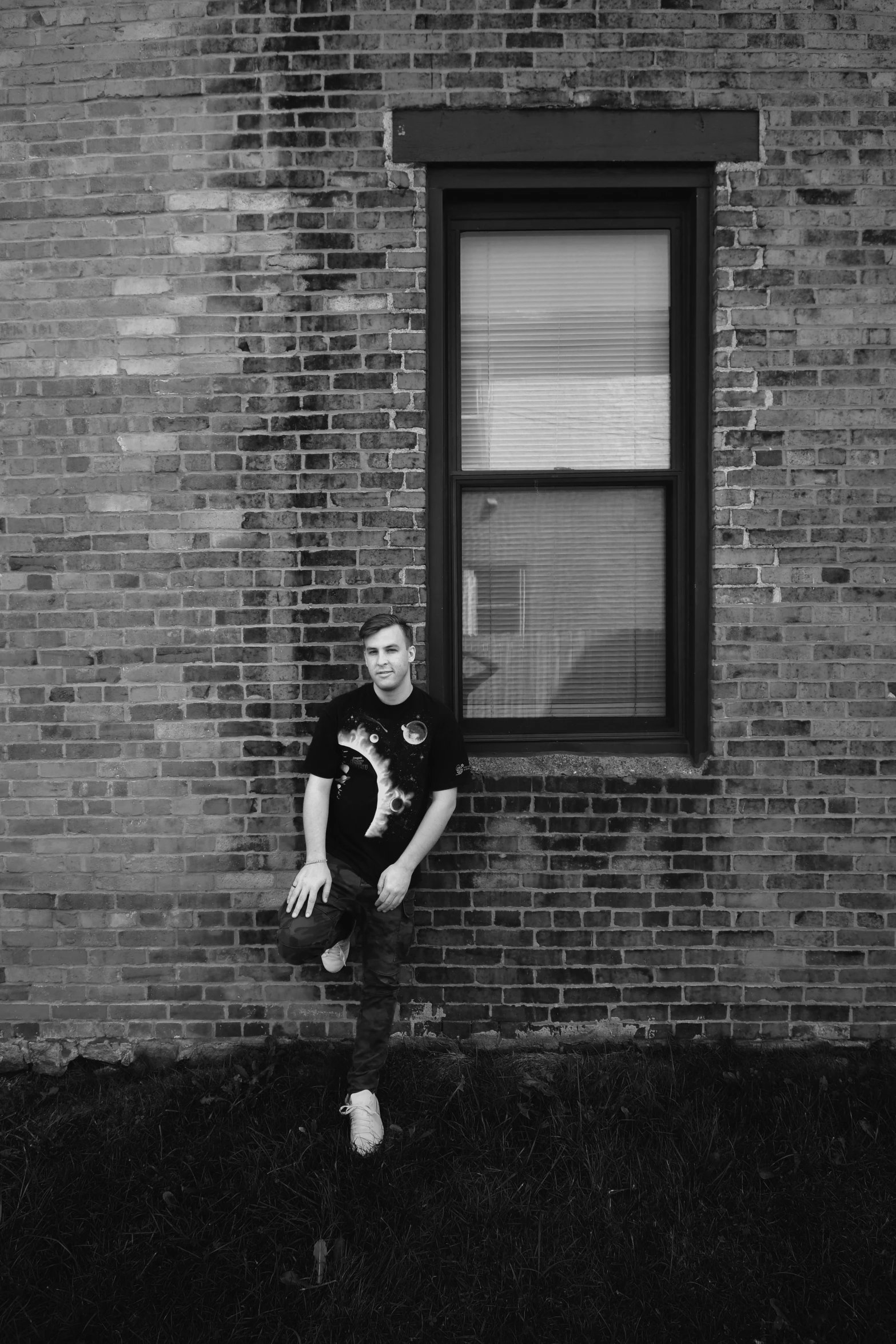 a man poses for a black and white po in front of a window