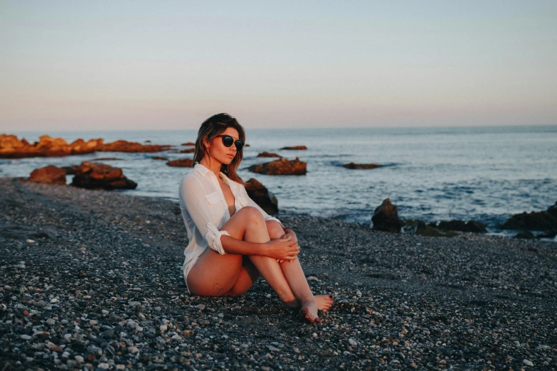 a woman is sitting on the beach posing for the camera