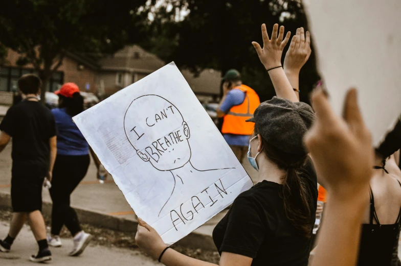 a protester holds up a sign as others walk by