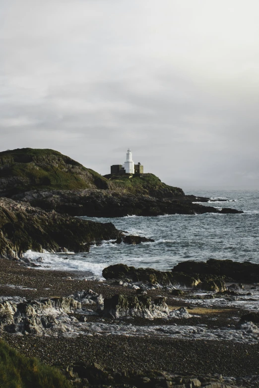 a lighthouse on the shore next to some rocks