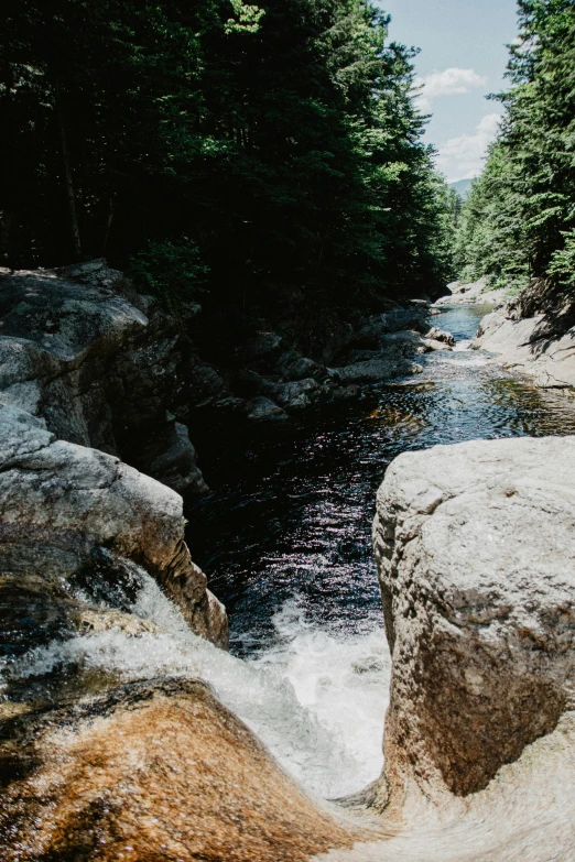 the view of a river flowing through the woods from the rocks