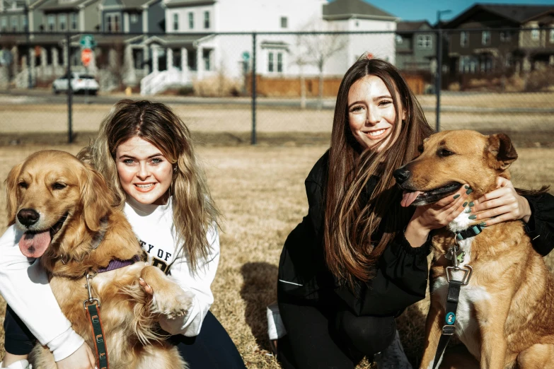 a couple of women with two dogs in front of some houses