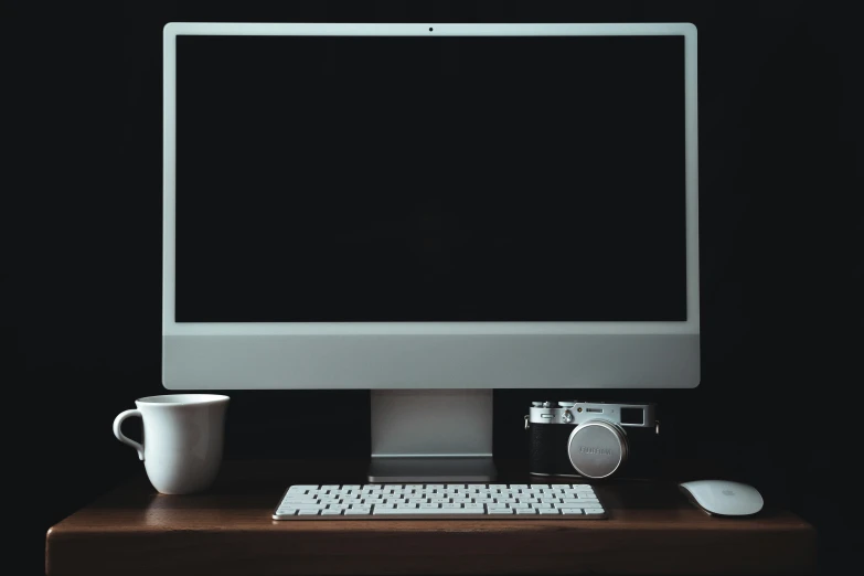 a computer monitor and coffee cup are sitting on a table