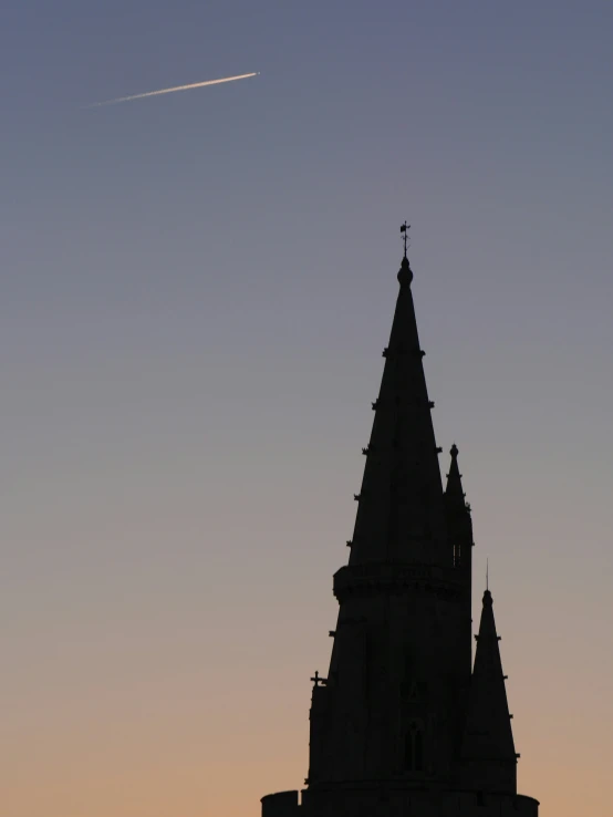 the view of an spire and clock tower from across the street