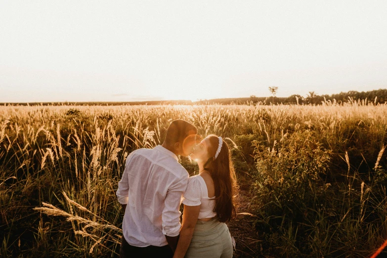 an engaged couple kissing in the sun, close to each other