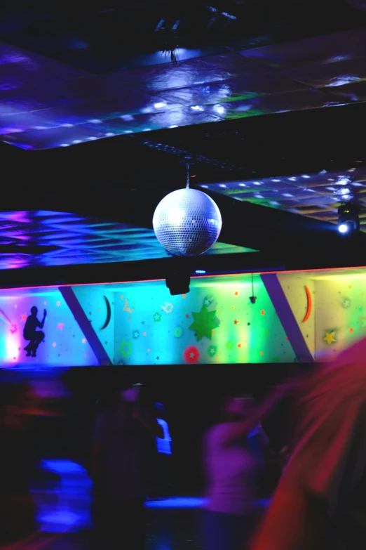 people are gathered around a dance floor with disco lights