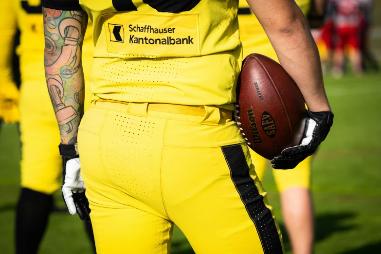 a closeup po of a football player with tattoos holding a football