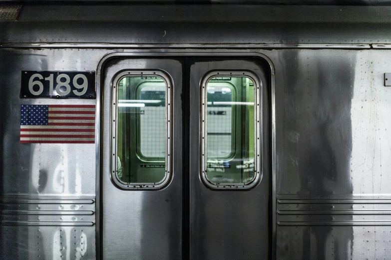 a silver subway car with a window and american flag on the door