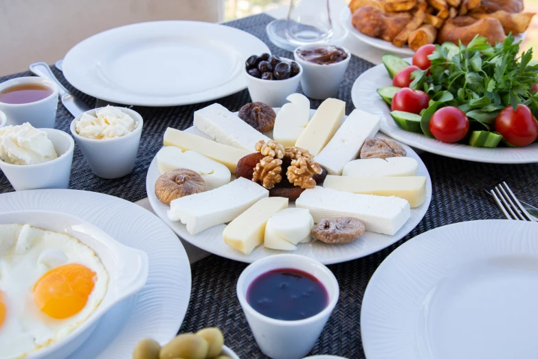 a table set for two with eggs, cheeses, and various food items