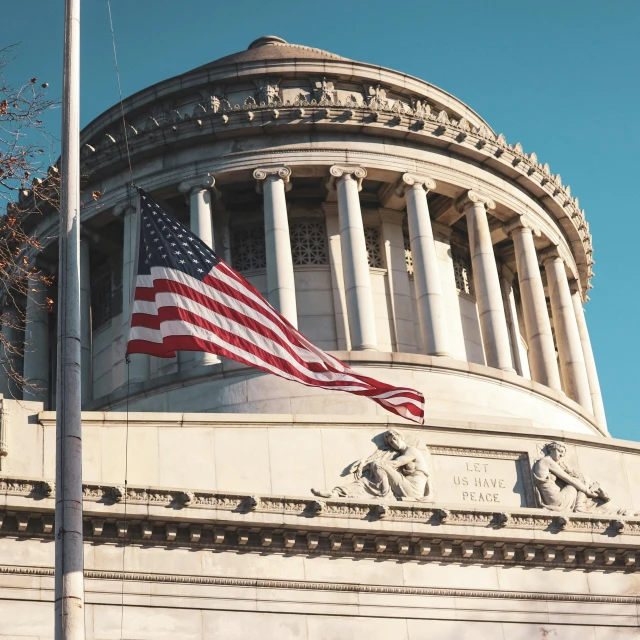 the american flag is flying at half mast in front of a domed building