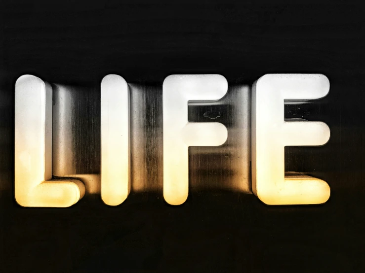 a illuminated sign that says life with a dark background