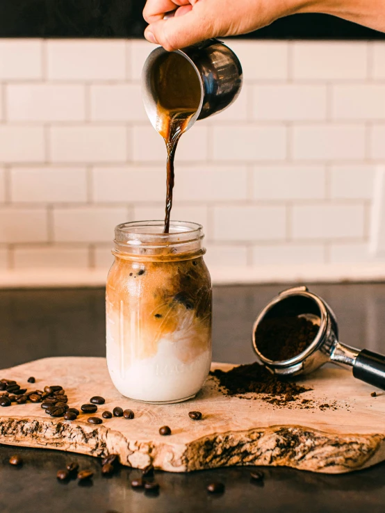 someone pouring coffee into a small jar