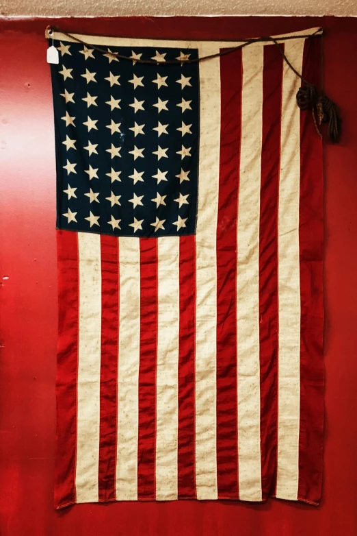 a big american flag hanging up against a red wall