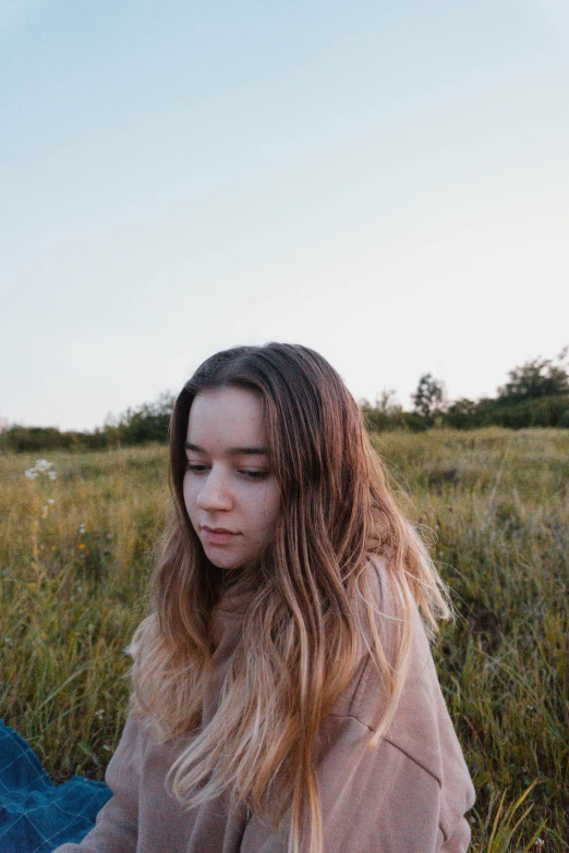 a girl with a light brown shirt looks at her cell phone