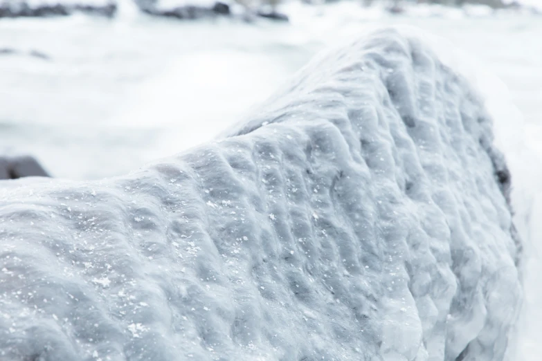 a snow covered rock sitting in the middle of the ocean