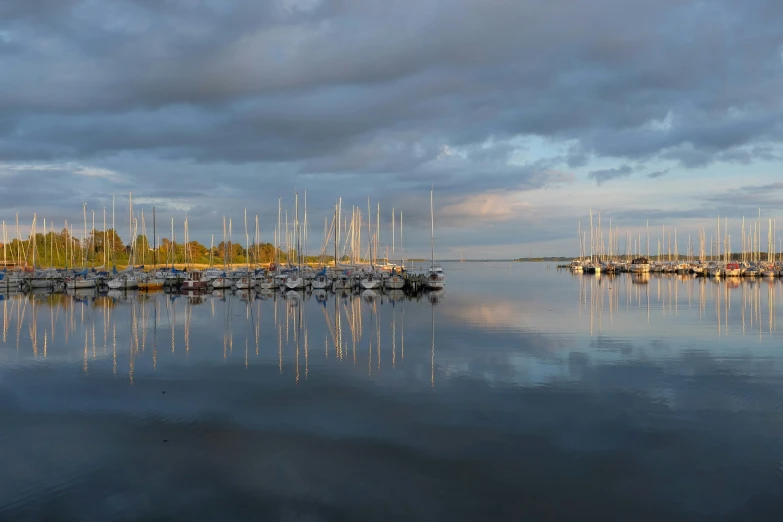 boats are parked on the water beneath a cloudy sky