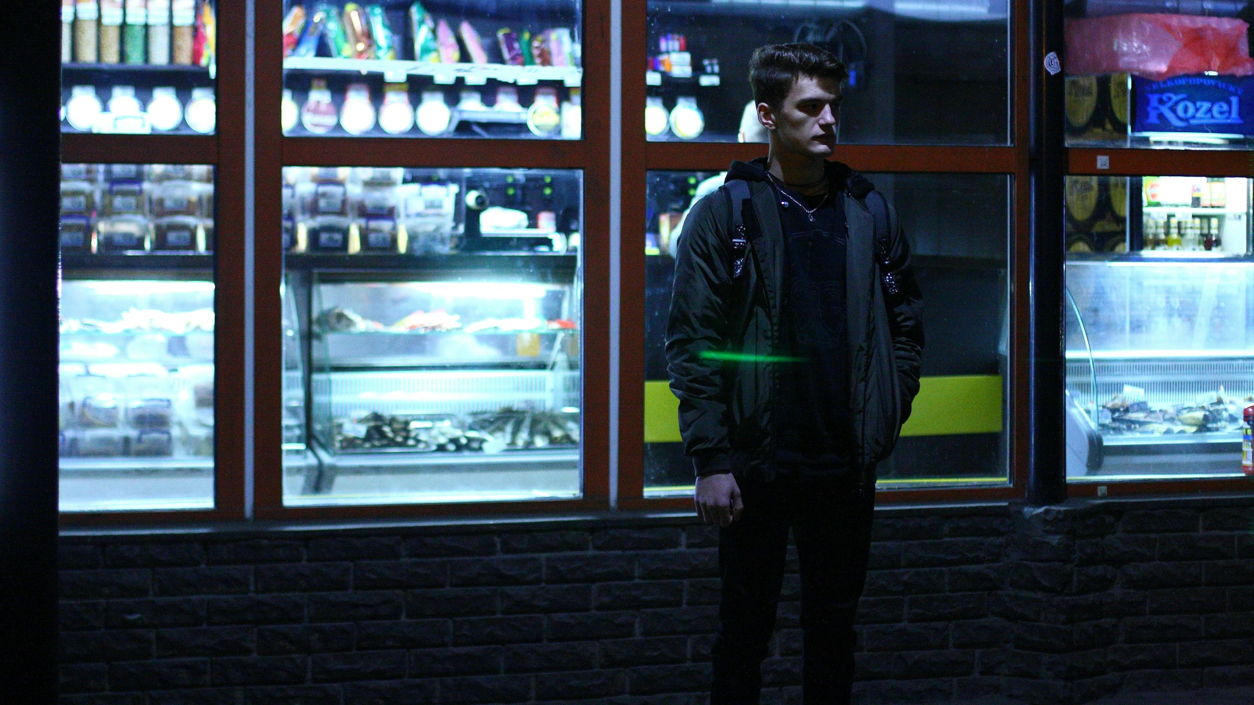 the man stands alone near some bottles in the window