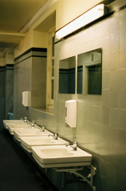 a long row of white sinks in a public restroom