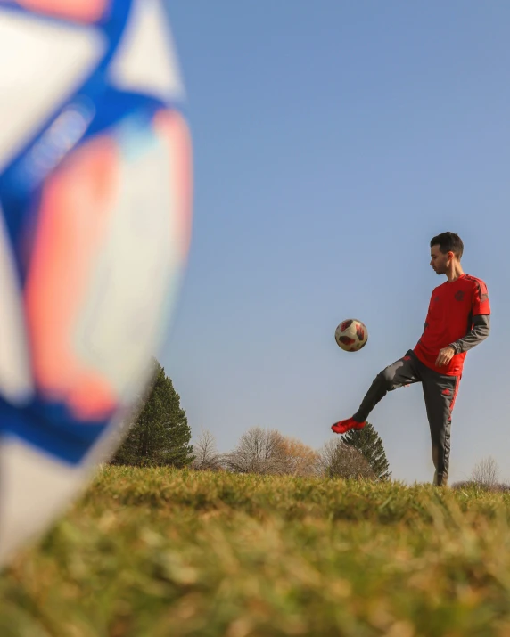 a man kicking a soccer ball in an open field