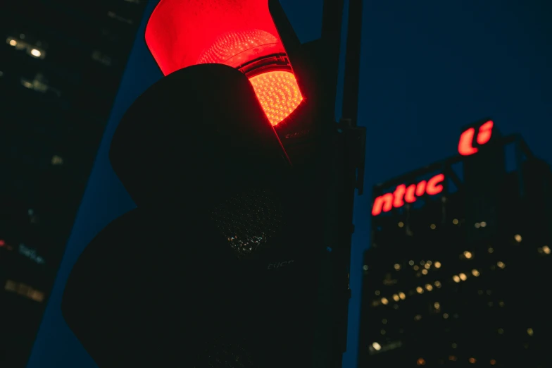 a red stoplight against a city skyline at night