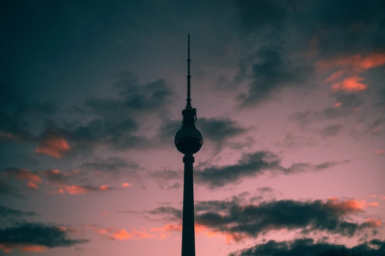 a very tall spire against a cloudy sunset