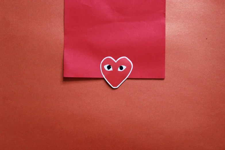 a square piece of paper with eyes made to look like a heart
