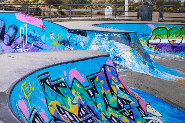 a skate park is covered in graffiti and has several ramps