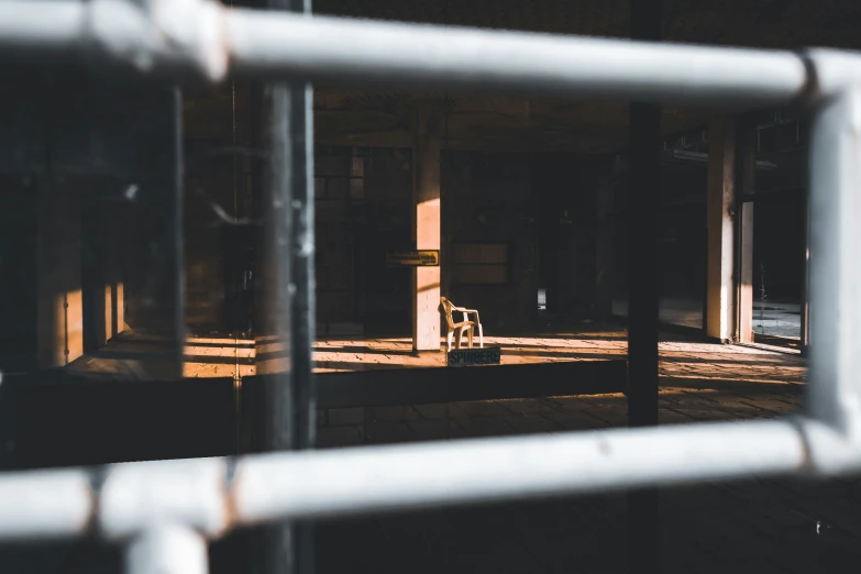 a chair is lit from a light through a fence