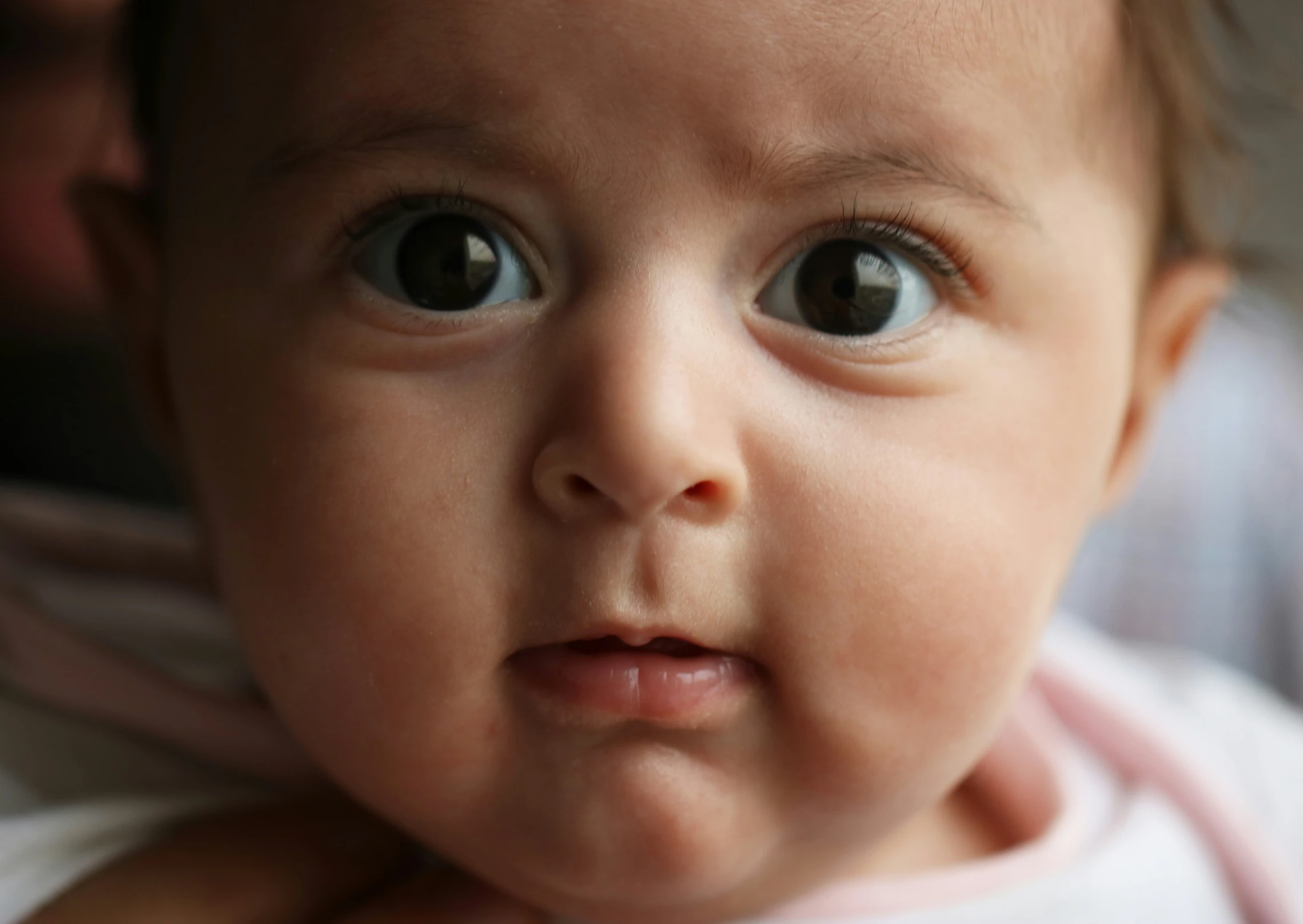 an infant looks up with large brown eyes