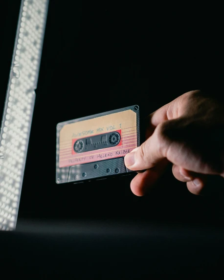 someone is holding a cassette in front of the computer