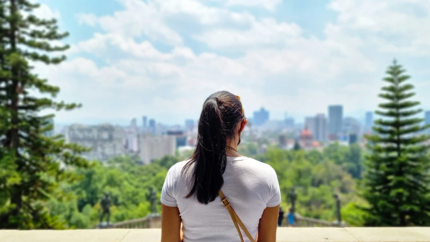 woman with long ponytail sitting on wall and looking over skyline