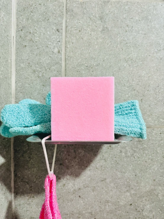 a hand holding a pink and blue soap