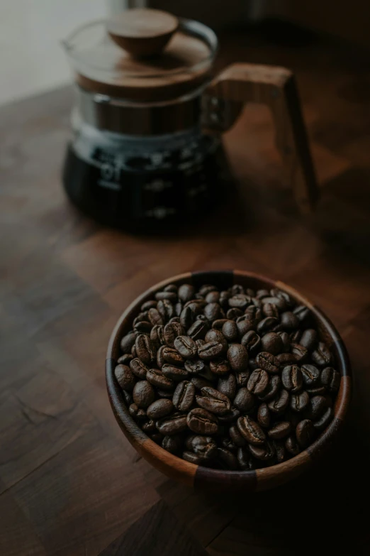 a coffee maker is shown next to a bowl of coffee beans