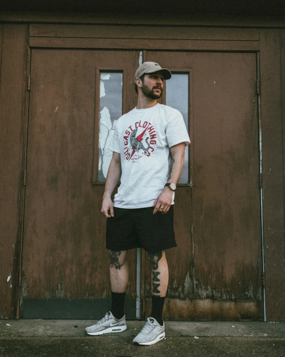 man in a hat standing in front of a barn