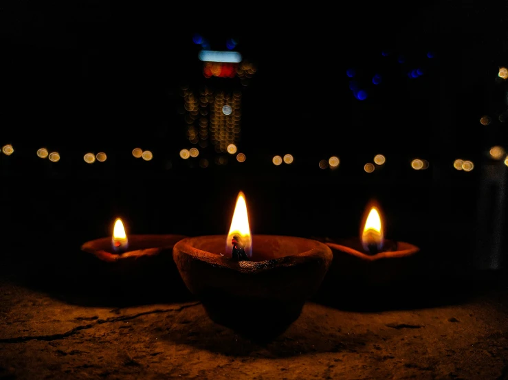 three lit candles on a stone surface at night