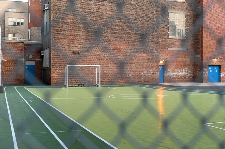 an alley with a soccer field and a soccer goal behind a fence