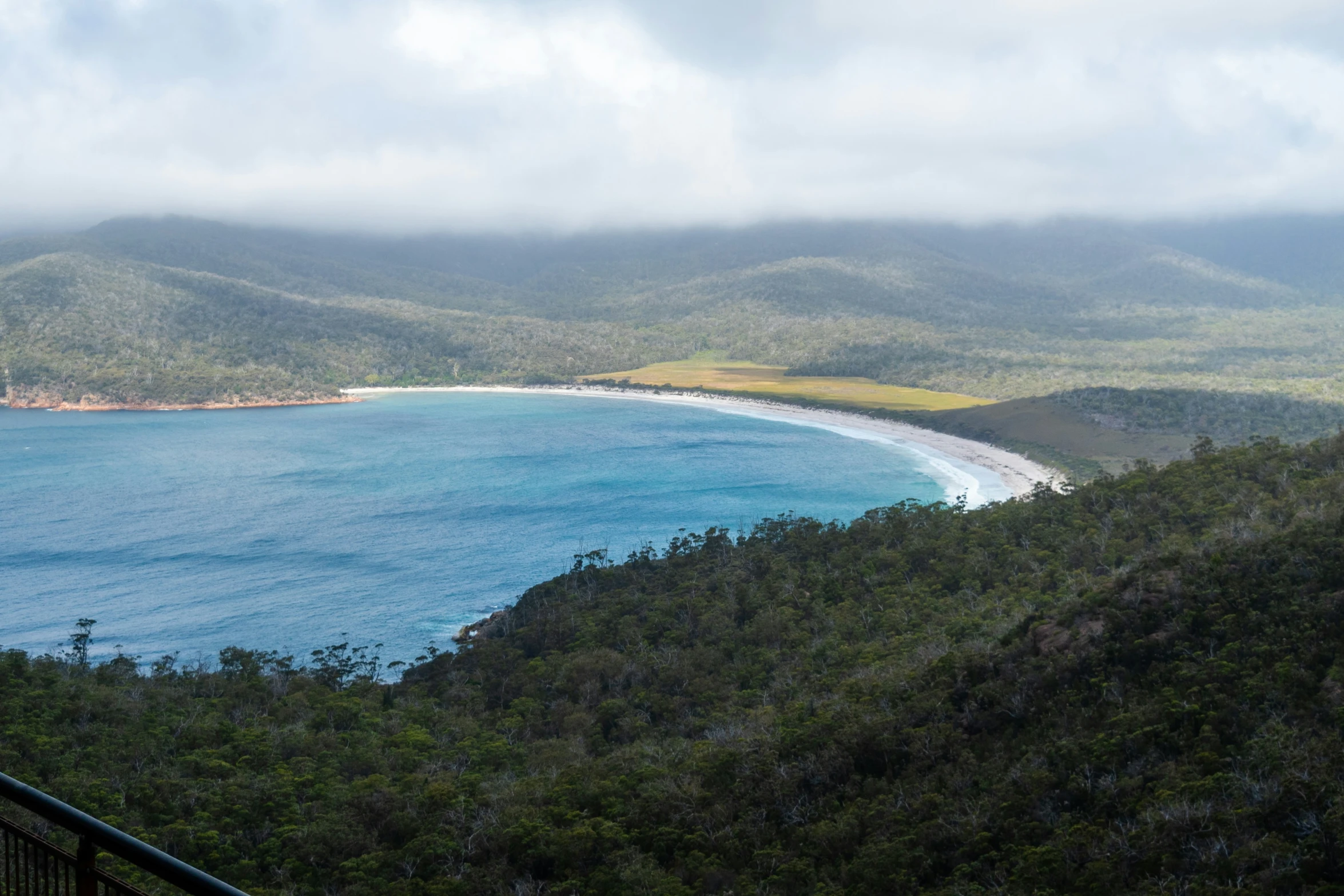 the view from atop a hill overlooking a beach and ocean