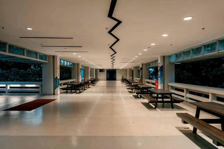 the inside of a building with many tables, benches and windows