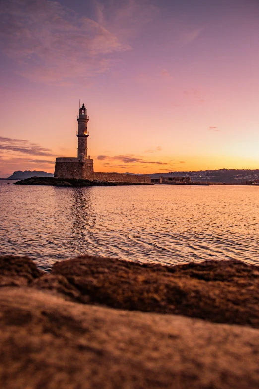 a lighthouse sitting on a rock by the water