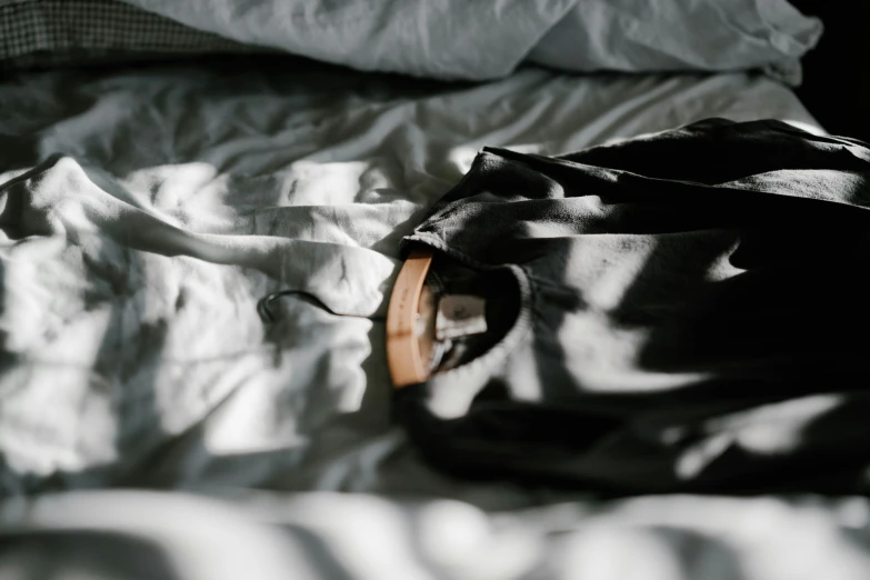 a black bag sitting on top of a bed covered in sheets