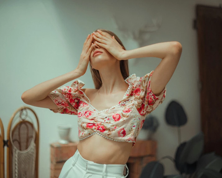 a woman with a crop top holding her hands over her eyes