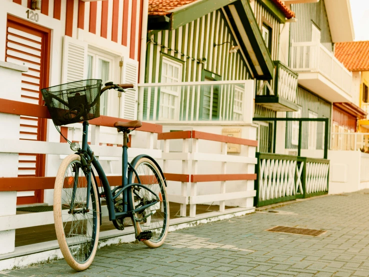 a bike parked by a fence on a brick road