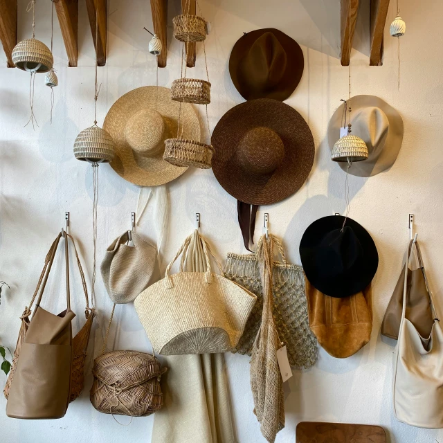 hats, hanging from hooks on a white wall