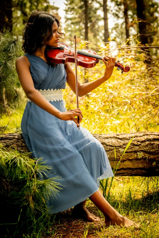 a woman in a blue dress plays the violin